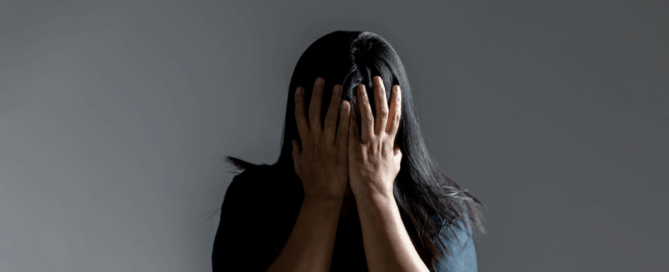 Person covering their face with both hands, expressing distress or overwhelm.