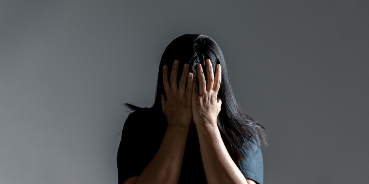 Person covering their face with both hands, expressing distress or overwhelm.