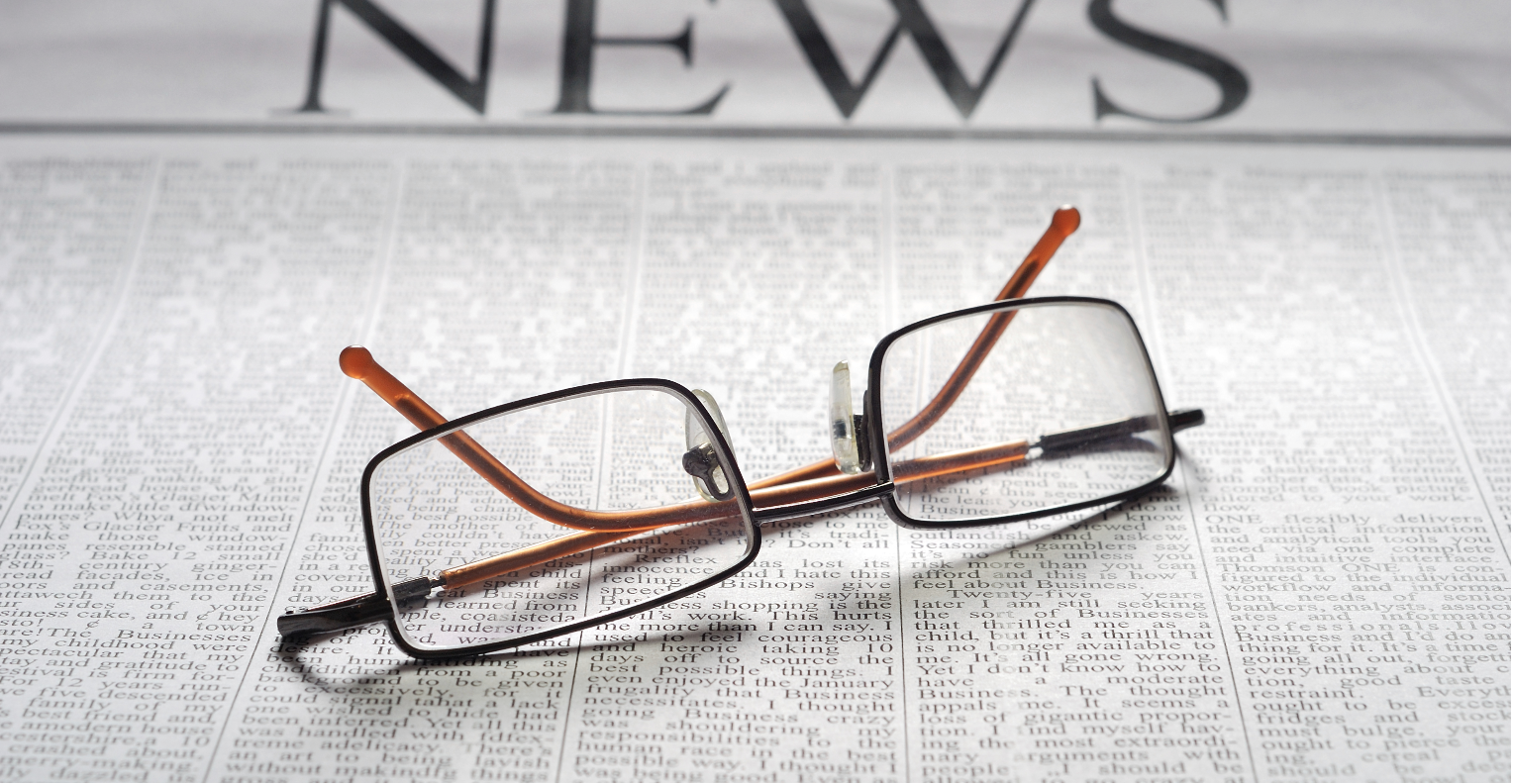 Photo of newspaper and reading glasses.