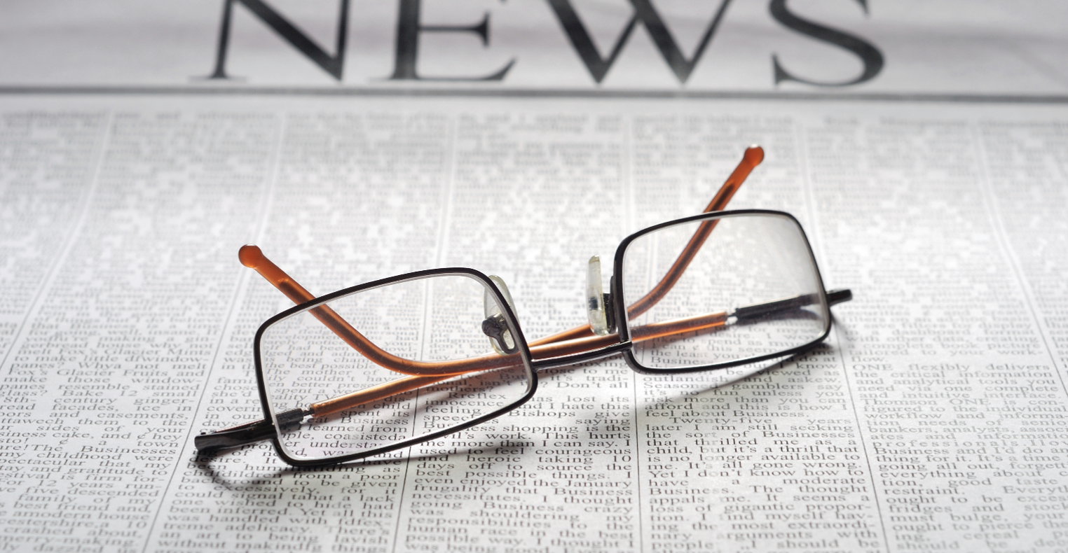 Photo of newspaper and glasses on top
