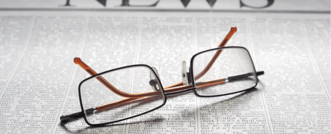 Photo of reading glasses on top of a newspaper.