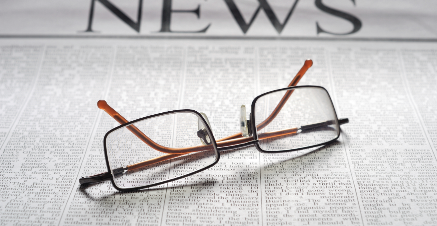 Photo of reading glasses on top of a newspaper.