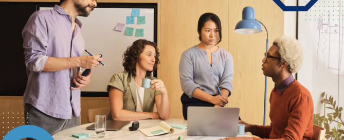 Four professionals meeting around a table with a laptop, discussing work in an office.